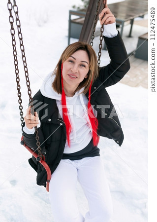 Carefree young woman riding on a swing in winter Carefree young woman riding on a swing in winter 112475489