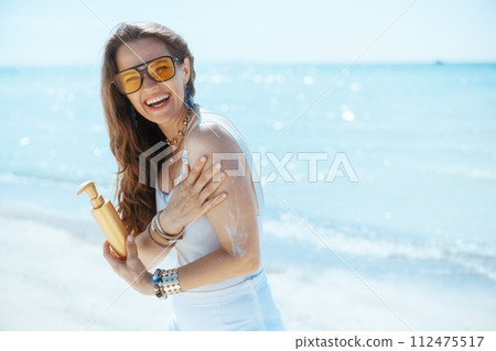 happy modern woman on ocean shore with sunscreen 112475517