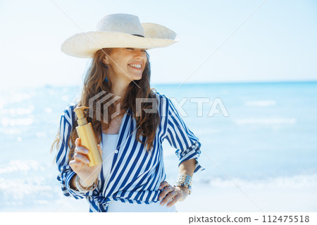 smiling elegant woman on beach with sunscreen 112475518