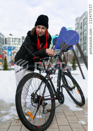A woman rented a bicycle to ride around the city in winter. A woman rented a bicycle to ride around the city in winter. 112475537