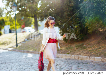 happy trendy woman in dress and jacket in city walking happy trendy woman in dress and jacket in city walking 112475874