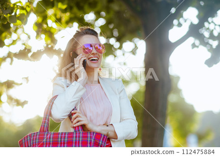 happy female in dress and jacket in city using smartphone happy female in dress and jacket in city using smartphone 112475884