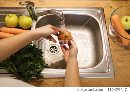 Top view of human's hand wash apples in kitchen sink. Vegetables and fruits Top view of human's hand wash apples in kitchen sink. Vegetables and fruits 112476447