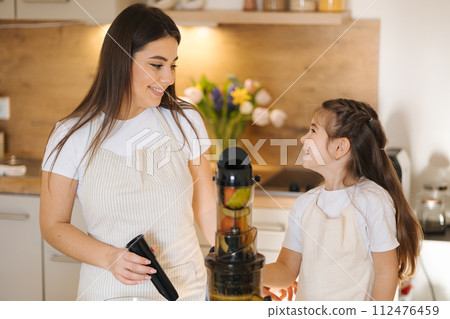 Mom and daughter making homemade healthy juice. Organic fruits and vegetables. Vegan beverage Mom and daughter making homemade healthy juice. Organic fruits and vegetables. Vegan beverage 112476459