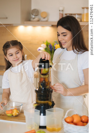 Mom and daughter making homemade healthy juice. Organic fruits and vegetables. Vegan beverage Mom and daughter making homemade healthy juice. Organic fruits and vegetables. Vegan beverage 112476461