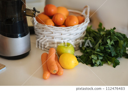 Different fruits and vegetables on table. Citrus fruits, lemon, tangerine, orange. Apple, carrots, celery, parsley. Juicer Different fruits and vegetables on table. Citrus fruits, lemon, tangerine, orange. Apple, carrots, celery, parsley. Juicer 112476483