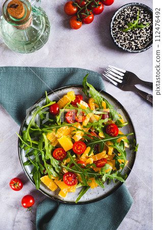 Dietary salad of orange slices, cherry tomatoes and arugula on a plate top and vertical view Dietary salad of orange slices, cherry tomatoes and arugula on a plate top and vertical view 112476492