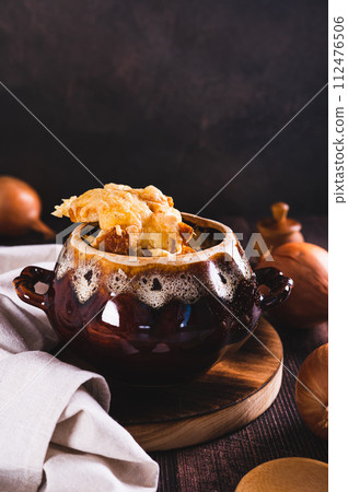 French onion soup with melted cheese and croutons in a pot on the table vertical view French onion soup with melted cheese and croutons in a pot on the table vertical view 112476506