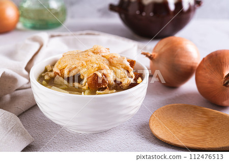 Homemade onion soup with croutons and cheese in a bowl on the table Homemade onion soup with croutons and cheese in a bowl on the table 112476513