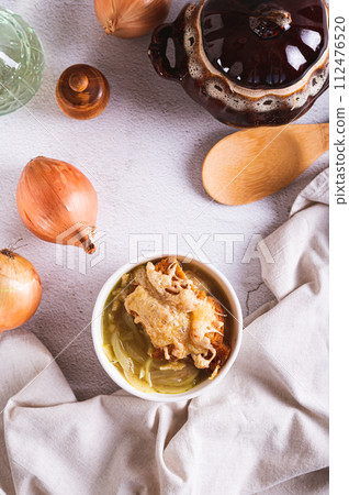 French onion soup with baked cheese bread in a bowl on the table top and vertical view 112476520