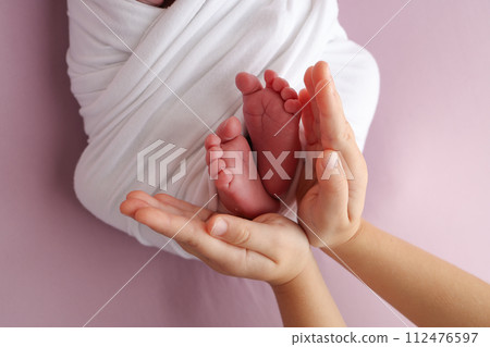 The palms of the father, the mother are holding the foot of the newborn baby in a white blanket, pink background. Feet of the newborn on the palms of the parents. photo child's toes, heels and feet. The palms of the father, the mother are holding the foot of the newborn baby in a white blanket, pink background. Feet of the newborn on the palms of the parents. photo child's toes, heels and feet. 112476597