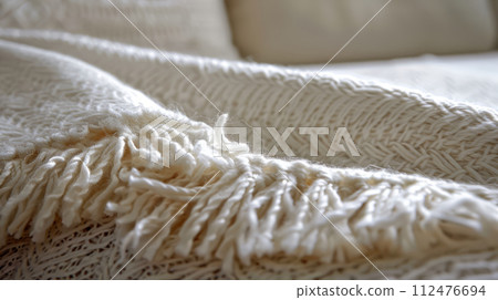 Close-up of a cozy woven blanket on a bed in a sunlit room. Cozy interior detail Close-up of a cozy woven blanket on a bed in a sunlit room. Cozy interior detail 112476694