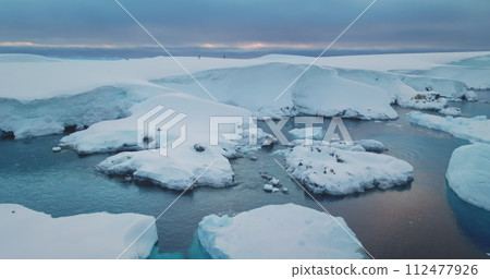 People ski on Antarctica snow hill glacier. Travel, active lifestyle, sport, recreation in Arctic wild nature landscape. Snow covered mountains, icy ocean, sunset winter scene. Aerial drone flight 112477926