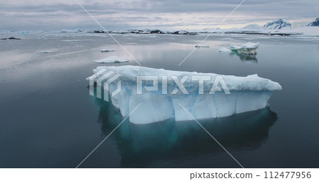 Dramatic melted iceberg from crashed glacier drift Antarctica ocean. Majestic winter Antarctic landscape. Ecology, melting ice, climate change, global warming concept. Aerial view drone panoramic shot Dramatic melted iceberg from crashed glacier drift Antarctica ocean. Majestic winter Antarctic landscape. Ecology, melting ice, climate change, global warming concept. Aerial view drone panoramic shot 112477956