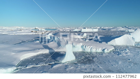Polar Iceland winter landscape aerial panorama. Frozen ocean, glaciers, icebergs, blue sky in sunny day. Untouched wilderness of Antarctica, South Pole. Desert white land of snow and ice drone shot. 112477962