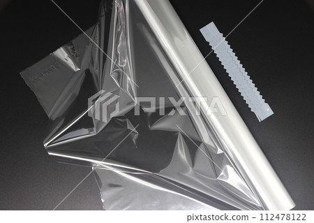 roll of white transparent film for baking with zippers on a black background, top view. roll of white transparent film for baking with zippers on a black background, top view. 112478122