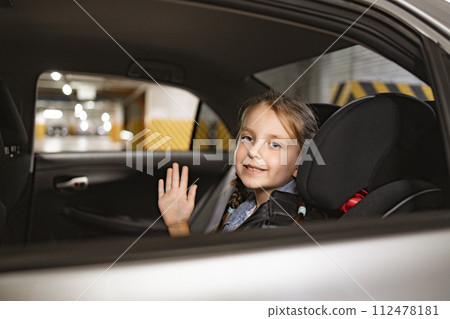 Caucasian little girl sitting on back seat of modern car in child chair. 112478181
