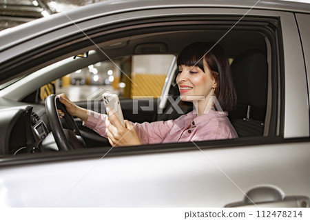 Caucasian woman sitting behind wheel of modern car with smartphone 112478214