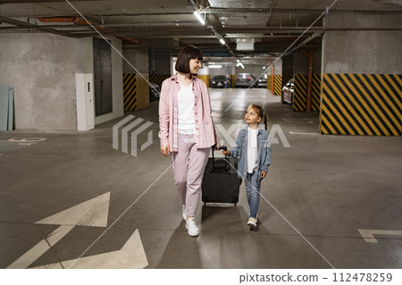 Young woman with child holding traveling suitcase as searching for car. Young woman with child holding traveling suitcase as searching for car. 112478259