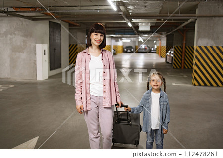 Young woman with child holding traveling suitcase as searching for car. Young woman with child holding traveling suitcase as searching for car. 112478261