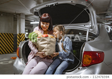 Caucasian mother and her little daughter, sitting comfortably in trunk. 112478394