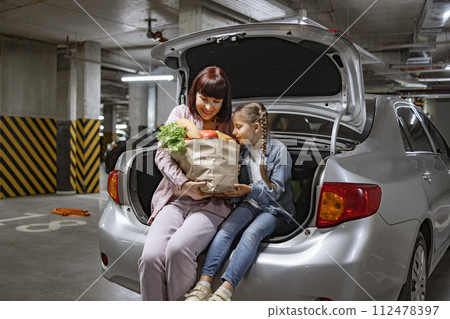 Caucasian mother and her little daughter, sitting comfortably in trunk. 112478397