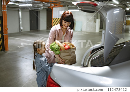 Caucasian mother and her daughter completed grocery purchasing at supermarket. 112478412