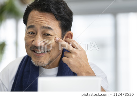 50多歲男子對著鏡子塗BB霜的男士化妝圖 50多歲男子對著鏡子塗BB霜的男士化妝圖 112478530