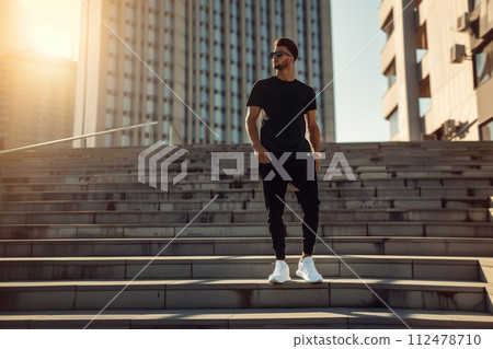 A man in a black shirt and black pants stands on a set of stairs 112478710