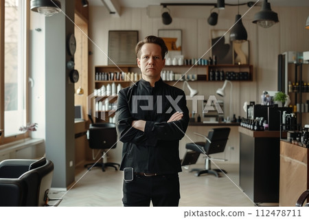 A man stands in front of a salon with his arms crossed 112478711