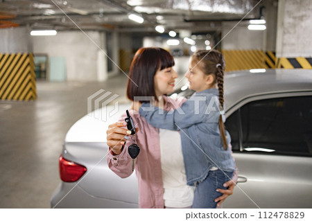 Attractive mother and daughter prepared keys to open car for weekend trip. Attractive mother and daughter prepared keys to open car for weekend trip. 112478829