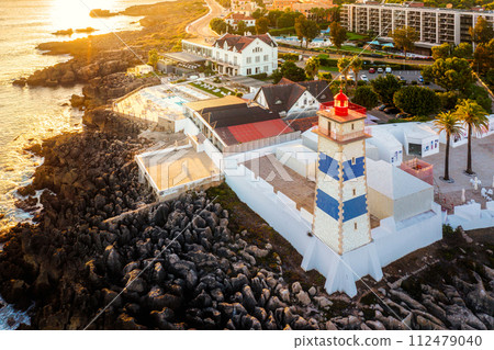 Aerial view of Santa Marta lighthouse, Cascais, Portugal before sunset on quiet sunny summer evening. Famous landmark by Cascais marina and Atlantic ocean coast near Lisbon.  112479040