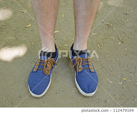 male feet with blue sneakers on the asphalt 112479104