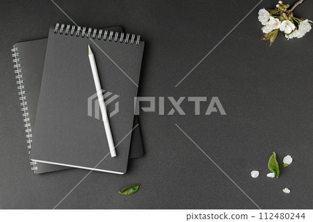 Two spiral notepads pencil and flowers. 112480244