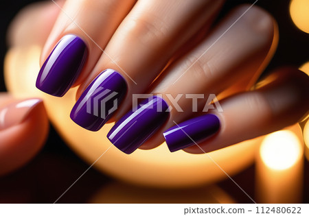 Close-up of a beautiful female hand with lilac nails on a dark blurred background of the spa salon. Conceptual hand care 112480622
