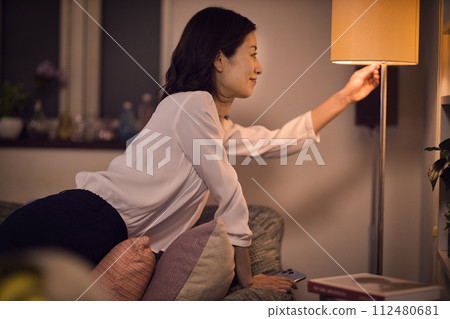 Night routine of a business woman who takes off her jacket and turns on the light at the stand. Night routine of a business woman who takes off her jacket and turns on the light at the stand. 112480681
