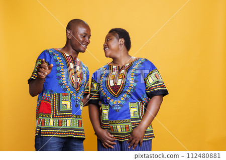 Happy black man and woman couple dancing and making moves together. Smiling wife and husband looking at each other with cheerful and romantic expression and posing in studio 112480881