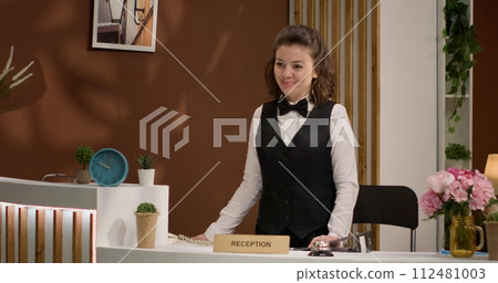 Woman employee reserves rooms online, talking to customers on landline phone call in hotel lobby. Reception staff using telephone line to welcome new guests at luxury resort, concierge services. Woman employee reserves rooms online, talking to customers on landline phone call in hotel lobby. Reception staff using telephone line to welcome new guests at luxury resort, concierge services. 112481003