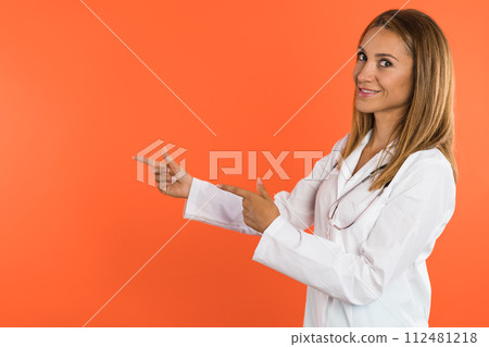 A young women doctor smiles in front of the camera and pointing with fingers 112481218