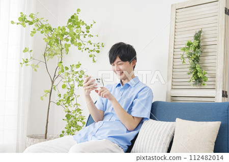 年輕人在客廳水平使用智慧型手機 112482014