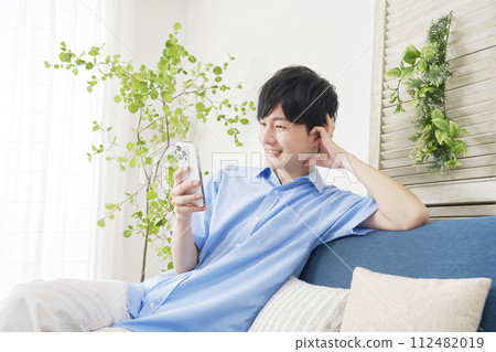 年輕人在客廳使用智慧型手機 112482019