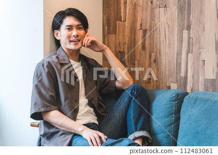微笑的亞洲/日本年輕男子在自家客廳放鬆（放鬆） 112483061