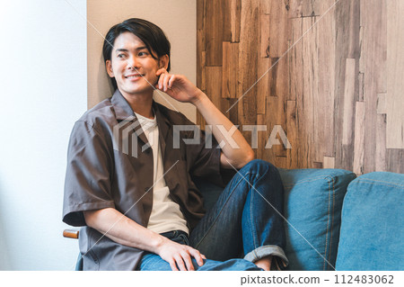 微笑的年輕亞洲/日本男子在自家客廳看電視/影片/影片（放鬆） 112483062