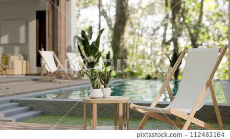 A lounge beach chair and a side table by the pool in a beautiful contemporary pool villa home. 112483164