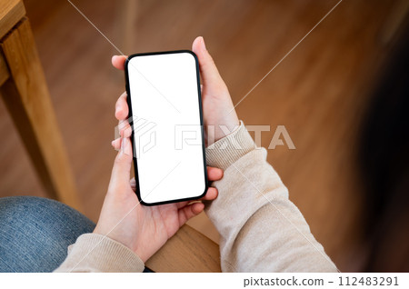 A white screen smartphone mockup to display your graphic ads is in a woman's hand. 112483291