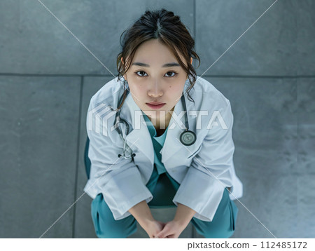 一位亞洲女醫生照顧表情嚴肅的病人的形象 112485172