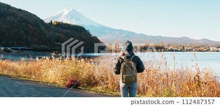 Woman tourist with Fuji Mountain at Lake Kawaguchi, happy Traveler sightseeing Mount Fuji in Fujikawaguchiko, Yamanashi, Japan. Landmark for tourists attraction. Japan Travel, Destination and Vacation 112487357
