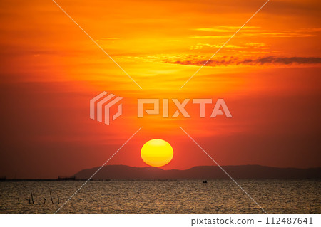 Sunset over island orange red sky with sun shine ray pass orange cloud in the evening 112487641