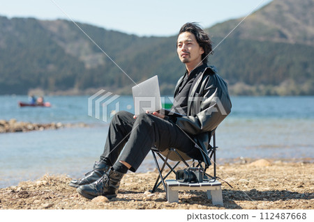 一名30多歲的男子在湖邊遠距工作 112487668