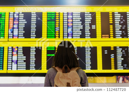 Young asian woman in international airport, checking flight at the flight information board 112487720